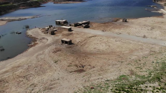 Several buildings destroyed by at water, forsaken Sfendili village at reservoir of Aposelemis dam, aerial shot. Low level at pond in dry summer time. One construction stay half in water