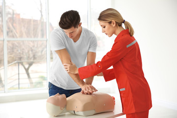 Young man practicing CPR on mannequin in first aid class