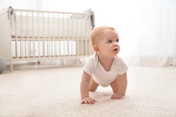 Fototapeten Cute little baby crawling on carpet indoors © New Africa