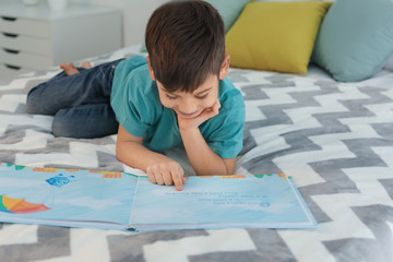 Obraz na płótnie Canvas Cute little boy reading book at home
