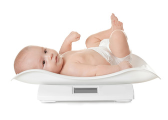 Cute little baby lying on scales against white background
