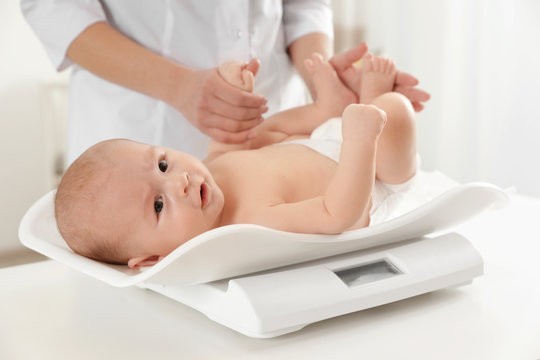 Doctor weighting baby on scales in light room