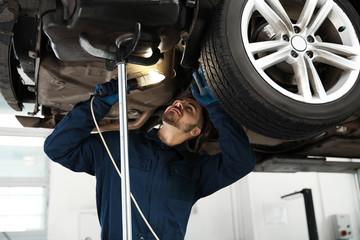 Technician checking modern car at automobile repair shop