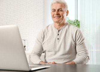 Mature man using video chat on laptop at home