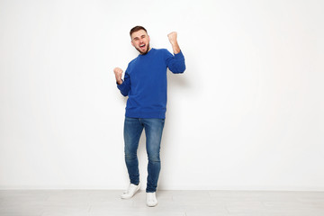 Full length portrait of emotional man against white wall. Space for text