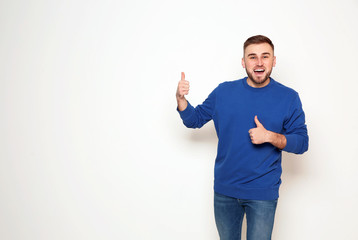 Portrait of emotional man showing thumbs up gesture on white background