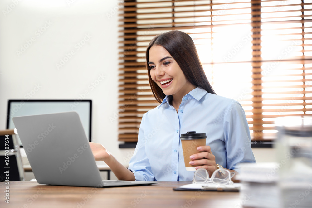 Wall mural Young woman using video chat on laptop in home office