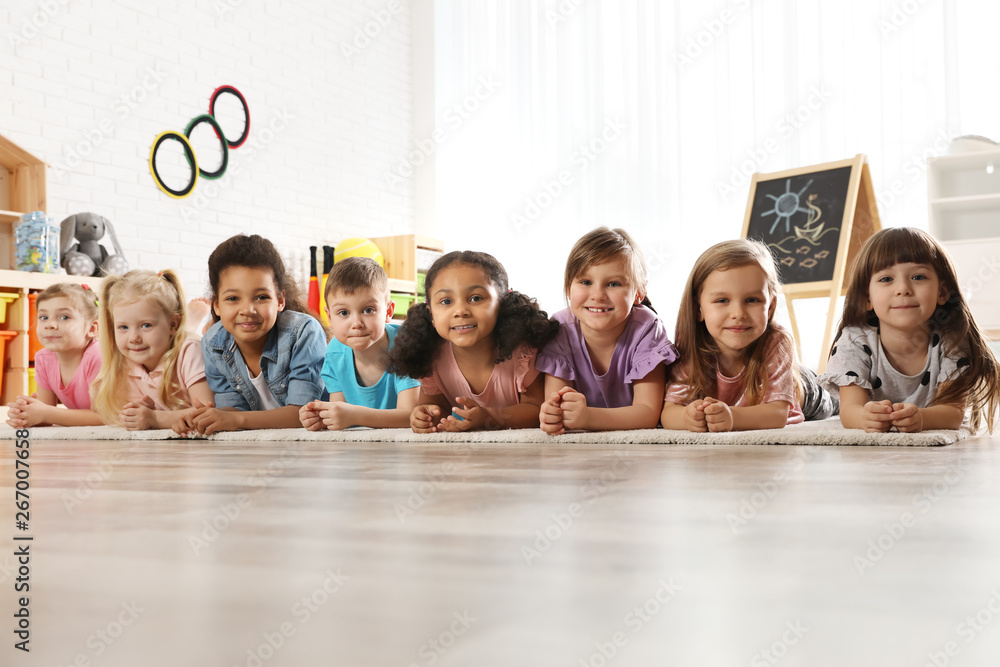 Poster group of cute little children lying on floor indoors. kindergarten playtime activities