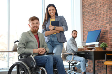 Plakat Young man in wheelchair with colleagues at office