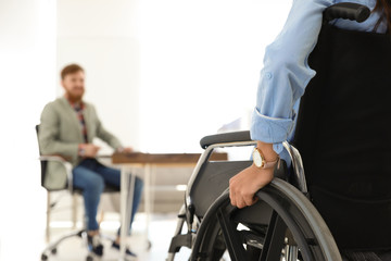 Obraz premium Young woman in wheelchair with colleague at office, closeup