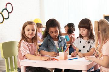 Adorable children drawing together at table indoors. Kindergarten playtime activities