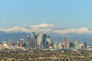 Downtown Los Angeles skyline with snow capped mountains behind at sunny day