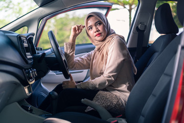 portrait of young Muslim woman in hijab sitting on car seat, car interior, female drivers concept.