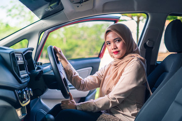Naklejka premium portrait of young Muslim woman in hijab sitting on car seat, car interior, female drivers concept.