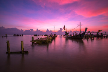 Fototapeta premium The blurred background of the morning twilight by the sea, changing the color of the beautiful sky, there is a fishing boat docked waiting to go out to find fish again.