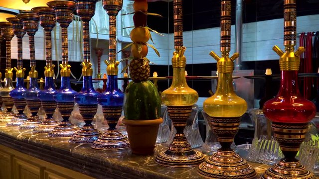 Zoom in view of colorful hookahs and fruit hookah stand on the bar counter in the cafe kitchen.