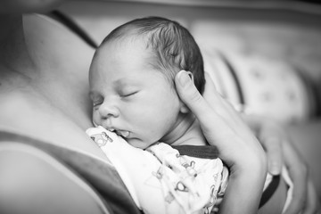 Beautiful baby sleeping in selective foxus, black and white. Close up portrait of newborn sleeping in mother's hands.