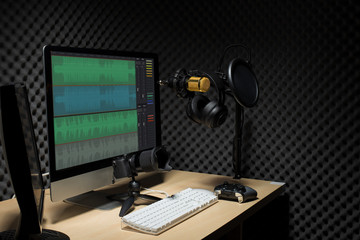 Microphone Condenser, gold mic hang over sound absorbing wall room with wave monitor keyboard mouse game pad controller and headphone in dark audio studio, low exposure lighting background copy space