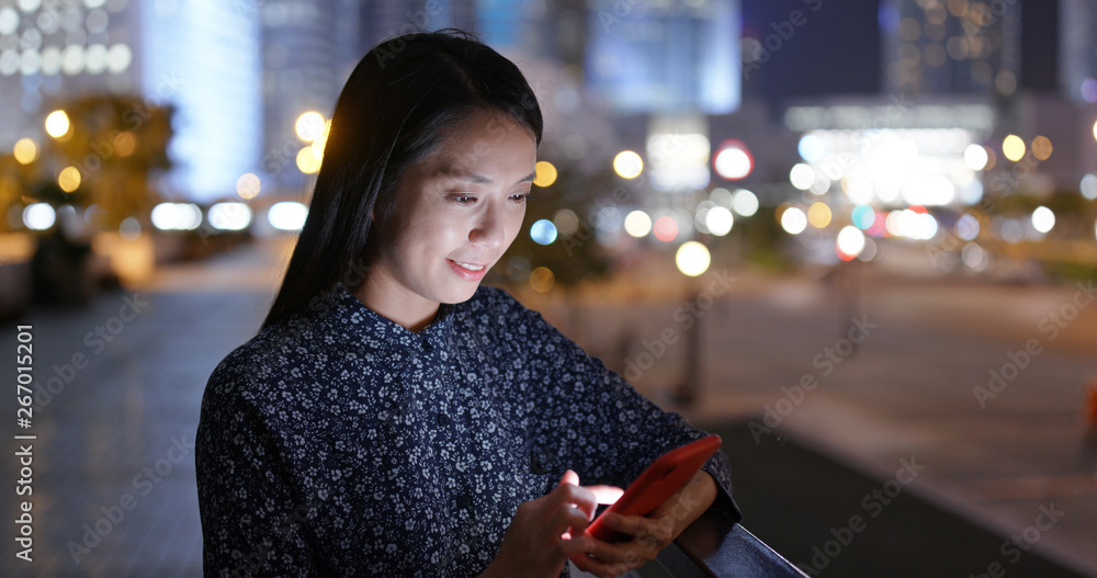 Wall mural woman use of cellphone online in city at night