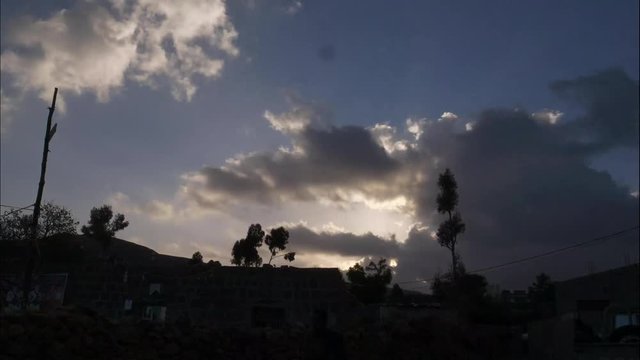 Fast timelaps shows clouds and sunrays unsecured with clouds and trees.