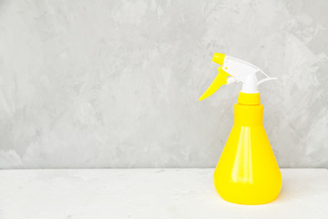 Simple yellow plastic hand spray bottle on gray background.