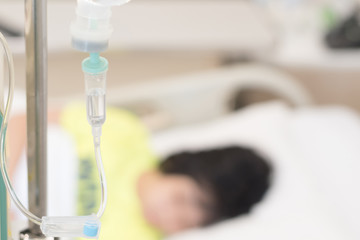 Child patient with IV line in hand sleep on hospital bed with mother's hand holding together to...