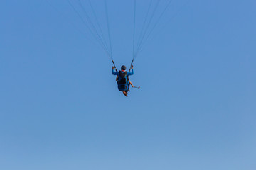 Obraz na płótnie Canvas Tandem paragliders floating across blue sky suspended on the equipment