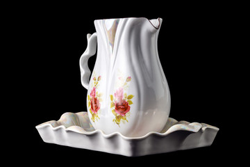 beautiful porcelain jug and tray with painted flowers, isolated on black