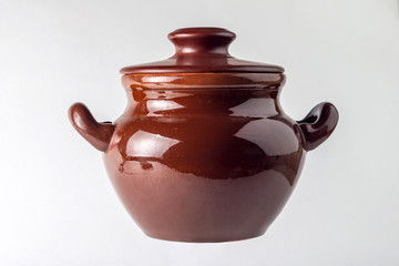 brown clay pot for stewing meat and vegetables on white