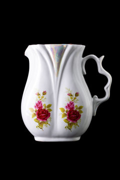 beautiful porcelain jug with painted flowers, isolated on black