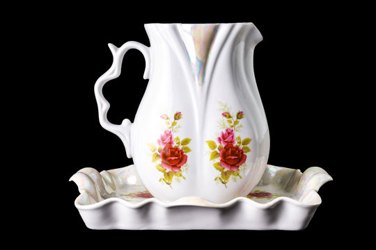 beautiful porcelain jug and tray with painted flowers, isolated on black