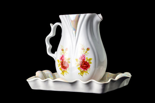 beautiful porcelain jug and tray with painted flowers, isolated on black