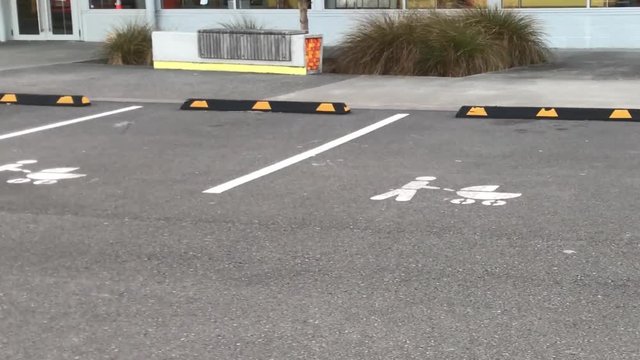 Right to left pan of parking lot specially marked for disabled and babies in prams