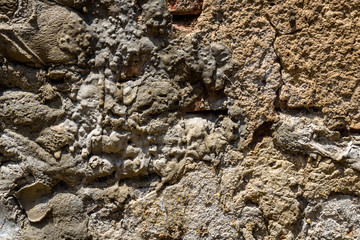 Old weathered masonry wall with crumbling brick and many cement patches, as a textured background