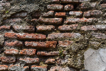 Old weathered masonry wall with crumbling brick and many cement patches, as a textured background