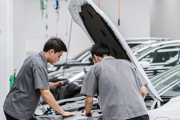 Asian mechanics open the car hood and checking the engine at maintainance service center for in...