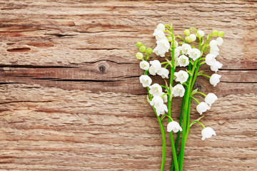 Lily of the valley flowers on brown wooden background