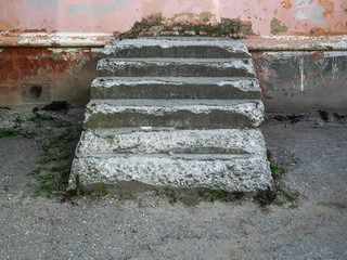An old, ruined concrete staircase rests against the wall. There is no way to go further
