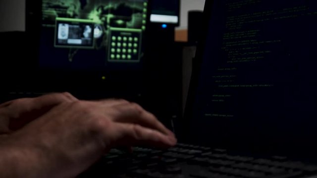 Computer hacker working in shadowy backroom coding.