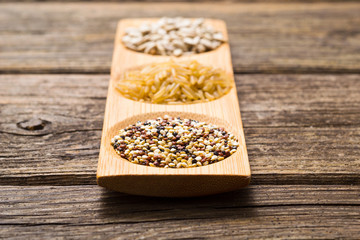 sunflower seeds, unpeeled rice, quinoa seeds on old wooden table