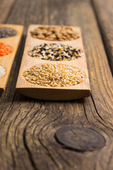 peeled and unpeeled sesame seeds, green lentils, old wooden table