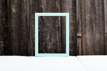 turquoise blue empty picture frame on white wood table, old wooden background