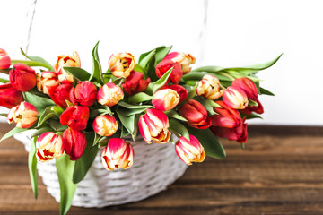 Fresh spring tulip. Bouquet of flowers in a basket on table.