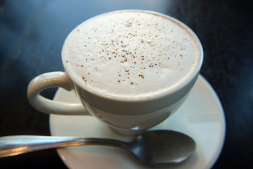 Cappuccino Cup with white foam and cinnamon macro photo.
