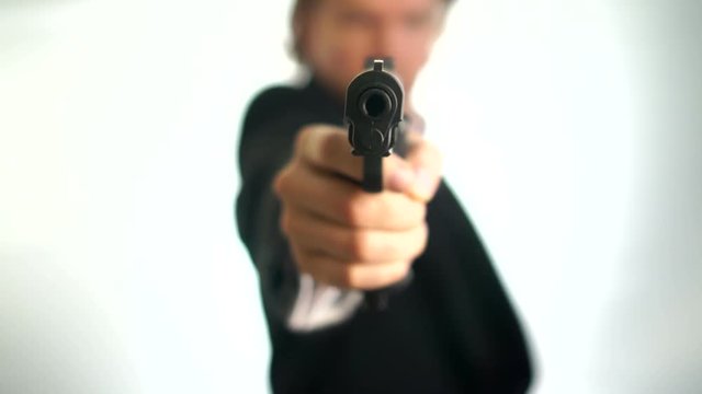 Gangster aim his gun at the camera.Man in suit aims his gun. A threatening stance, aiming down the sights of his pistol, police, mafia criminal or mercenary. Focus is on the barrel with a one hand pis