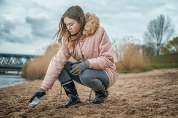 Young woman is cleaning the beach from plastic waste