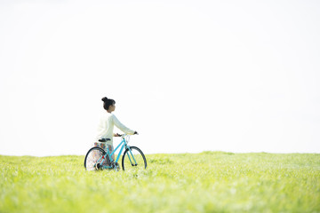 草原で自転車を押す女性の後姿