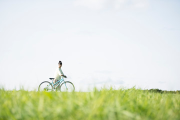 草原で自転車を押す女性