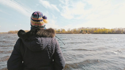 A woman with a woolen cap and a warm coat is looking at the Dnieper river, in Kiev, Ukraine, during...