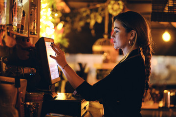 Concepto pequeño negocio o emprendimiento personal: una joven camarera en la máquina registradora...